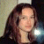 Pixelated static image of a person with long dark hair, light skin tone, and neutral expression against blurred background.