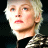 Pixelated close-up of a person with light-colored hair wearing dark clothing against a black background, rendered in low-resolution 48x48 pixels.