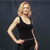 Pixelated image of a person with light hair wearing a black sleeveless top against a dark background.