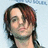 Pixelated static image of a person with dark brown hair and light skin, wearing a dark top against a light blue background.