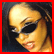 A pixelated image of a person with dark hair, wearing black sunglasses and red lipstick, shown in two side-by-side against a solid red border
