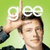 A person with short dark hair makes a hand gesture above their head against a green background, with the text "gee" in white letters positioned over the top of the image.