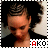 A person with dark curly hair styled in braids wears a black top against a light background, with text reading AKO below.
