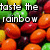 Pixelated image with bold text 'taste the rainbow' overlaid on a colorful assortment of pixelated fruit shapes.