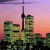 Pixelated cityscape with tall buildings and a tower against a pink-orange gradient sky, next to green text reading 'Original Icons .com' on dark background.