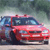 Pixelated image of a red sedan with blue accents parked on a light-colored surface against a blurred greenish background.