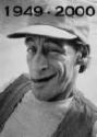 Black-and-white static image of a smiling man wearing a cap and jacket with visible text "1949 - 2000" above his head.