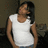 Pixelated image of a person in a white tank top with dark hair, standing against a muted brown background.