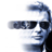 Pixelated static icon of a person wearing dark sunglasses with white highlights on the lenses, blue-gray hair, and a black garment visible on the right side against a plain white background.
