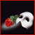 A white mask with a red rose and green leaves rests on a dark background, accompanied by stylized text reading "The Phantom of the Opera is inside your mind.".