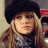 A static image shows a person with long blonde hair wearing a black beret and dark turtleneck, next to green text reading 'OriginalIcons.com' on a solid background.