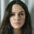 Pixelated close-up of a person with long dark hair against a light gray background, showing partial facial features including eyes, nose, and lips.