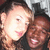 Two people in close proximity, one with light skin and short brown hair, the other with darker skin and curly brown hair, both smiling against a dark background.