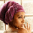 A pixelated side profile of a person with brown skin and purple hair wrapped in a towel, holding a hand near their face against a light background.