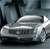 Pixelated silver sedan with visible grille text, set against a dark abstract background with vertical shapes.