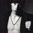 Pixelated static image of a figure in white attire with a chain necklace against dark background, right side shows partial hand gesture.