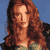 Static pixelated image of a person with long red hair against blue background, wearing green top and dark outer garment.