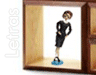 A woman in a black dress stands inside a wooden display case with one hand on her hip, blue shoes visible.