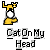 Yellow cat with white face and black eyes stands on a yellow arm, head tilted back, above text reading Cat On My Head.