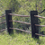 Pixelated static image of a wooden fence with two vertical posts and horizontal rails against a blurred green background.