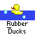 Yellow rubber duck with brown beak floats on blue water, surrounded by green and light-blue bubbles; text 'Rubber Ducks' appears below in pixelated font.