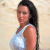 Static pixelated image of a person with long dark hair wearing a light blue sleeveless top against a beige background.