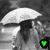 A grayscale image of two figures under a white umbrella with a heart symbol changing color in the corner.