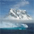 Pixelated image of a large white iceberg floating in dark blue water under a light blue sky with faint clouds.