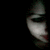 A pixelated close-up of a person's face with dark hair, visible eye, and light skin tone against a black background.