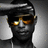 Pixelated static image of a person wearing dark sunglasses with orange-tinted lenses and a black cap, set against a gray gradient background.