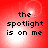 Red background with four identical displaying pixelated text 'the spotlight is on me' in black font over a white light effect
