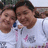 Two people in white shirts with pink and blue accents pose closely together against a light background.