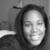 A grayscale pixelated image of a person with closed eyes and a slight smile, wearing dark hair and a hooded garment against a plain background.