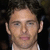 Pixelated close-up of a person's face with dark hair, light skin tone, and neutral expression against dark background.