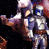 Pixelated static image of two armored figures in dynamic pose against dark background with red and purple accents.