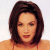 Static pixelated image of a person with shoulder-length dark brown hair wearing an orange top against a light background.