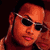 Pixelated static image of a person with orange skin tone wearing dark sunglasses and pink lips, cropped to show only the upper face against a black background.