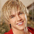 Static 50x50 pixel icon showing a close-up of a person with blonde hair wearing red clothing and dark earrings, rendered in low-resolution pixel art style.