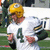 Pixelated image of a person wearing a yellow helmet and white jersey with dark green number 4, standing on grassy field.