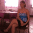 A pixelated image of a person in a strapless blue and purple dress sitting on a dark chair against a pinkish background.