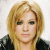 Static pixelated image of a person with blonde hair and dark clothing against a light background.
