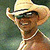 Static pixelated image of a person wearing a cowboy hat and sunglasses with visible necklaces against a blurred green background.