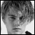Black-and-white pixelated static image of a person's face with short hair, visible facial features including eyes and mouth, and partial shoulder in grayscale tones.