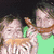 A pixelated image shows a person in green shirt holding an orange object, with four people in blue shirts standing behind them.