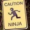 Yellow rectangular sign with black border displaying 'CAUTION' at top, running figure icon, and 'NINJA' at bottom.