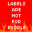 Red background with white pixelated text reading 'LABELS ARE NOT FOR PEOPLE' and orange flame-like shapes at the bottom.