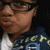 A person wearing glasses and a dark blue hoodie with yellow text over a white shirt, shown in four with slight variations