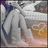 Pixelated static image of a figure in white attire holding a golden object against a gradient background with purple, blue, and orange hues.