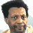 Pixelated image of a person with short dark hair and light skin, wearing a light-colored shirt against a bright background.