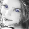 A grayscale close-up of a person's face with blue-tinted eyes, showing a slight smile and visible hair strands.